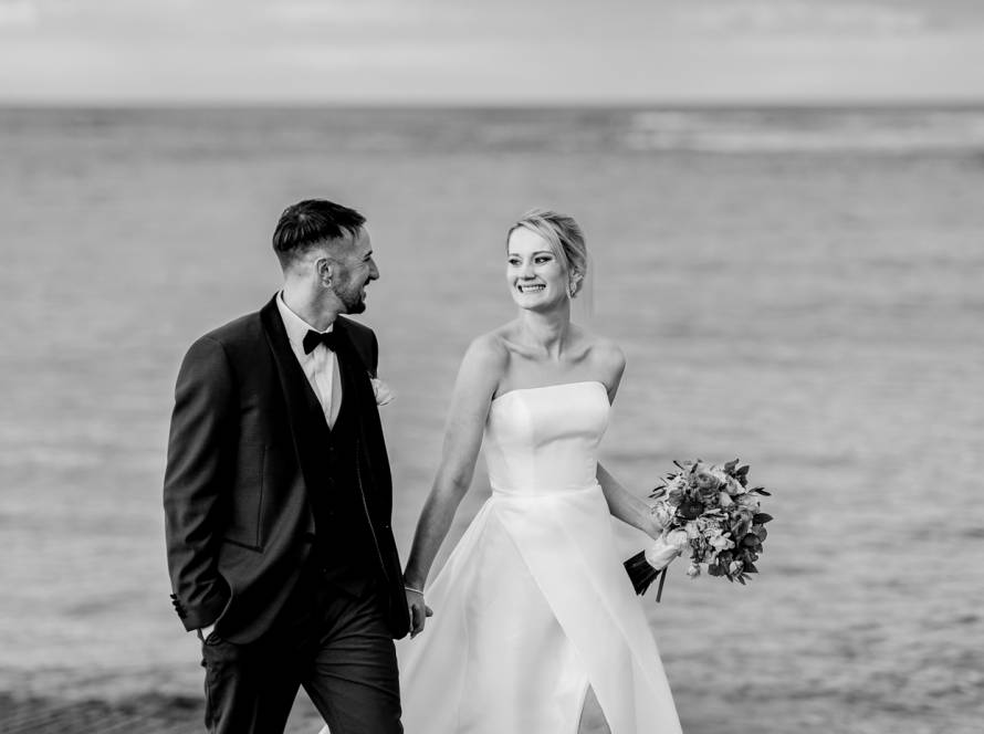 Bride and groom walking together by the water