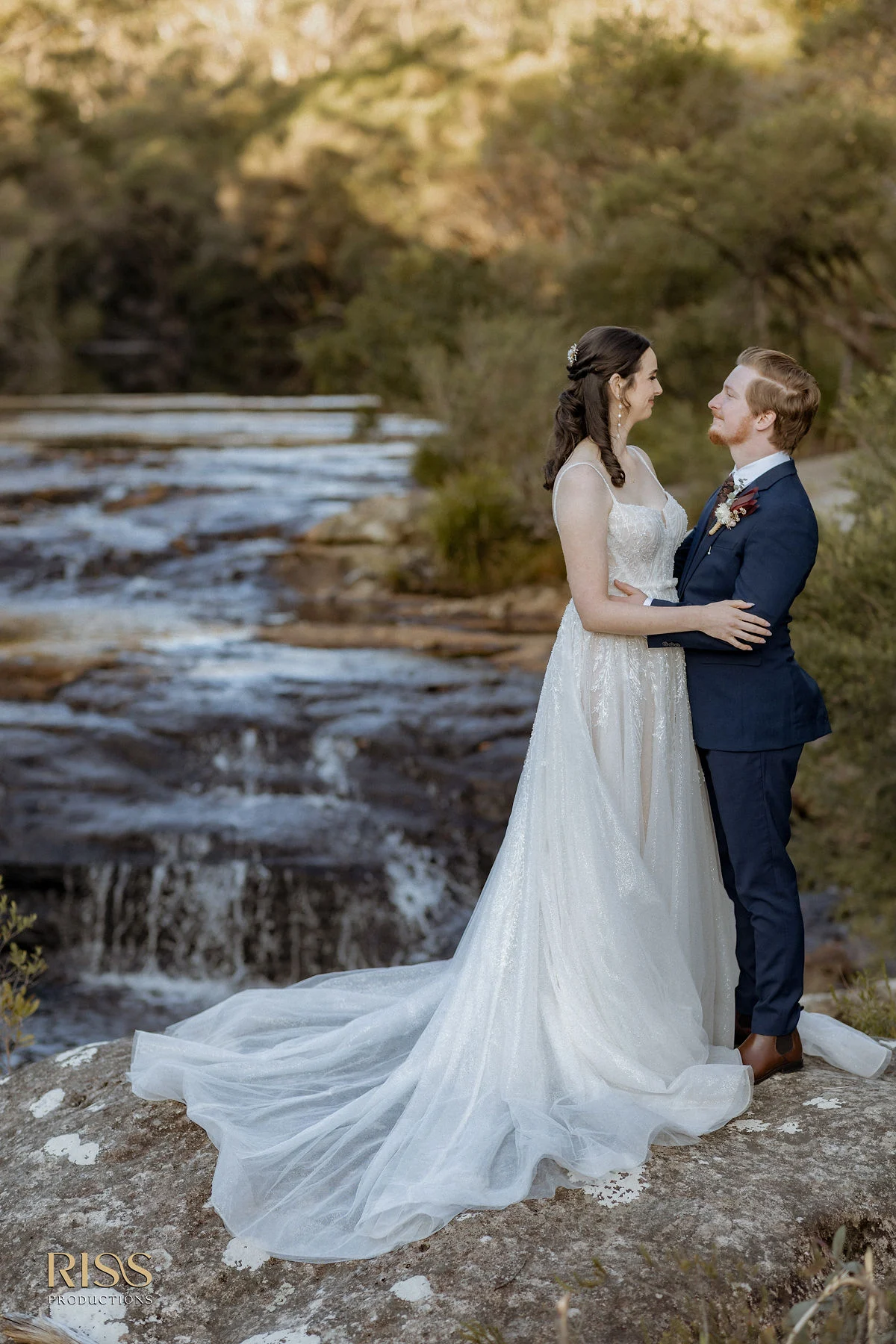 Caitlin and Jakub embracing beside a waterfall in the Southern Highlands