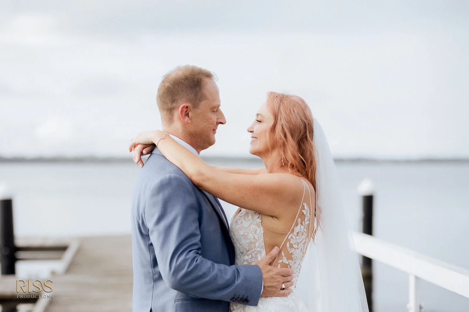 Jenny and Steve embracing by the water at the Beachcomber Hotel, Toukley