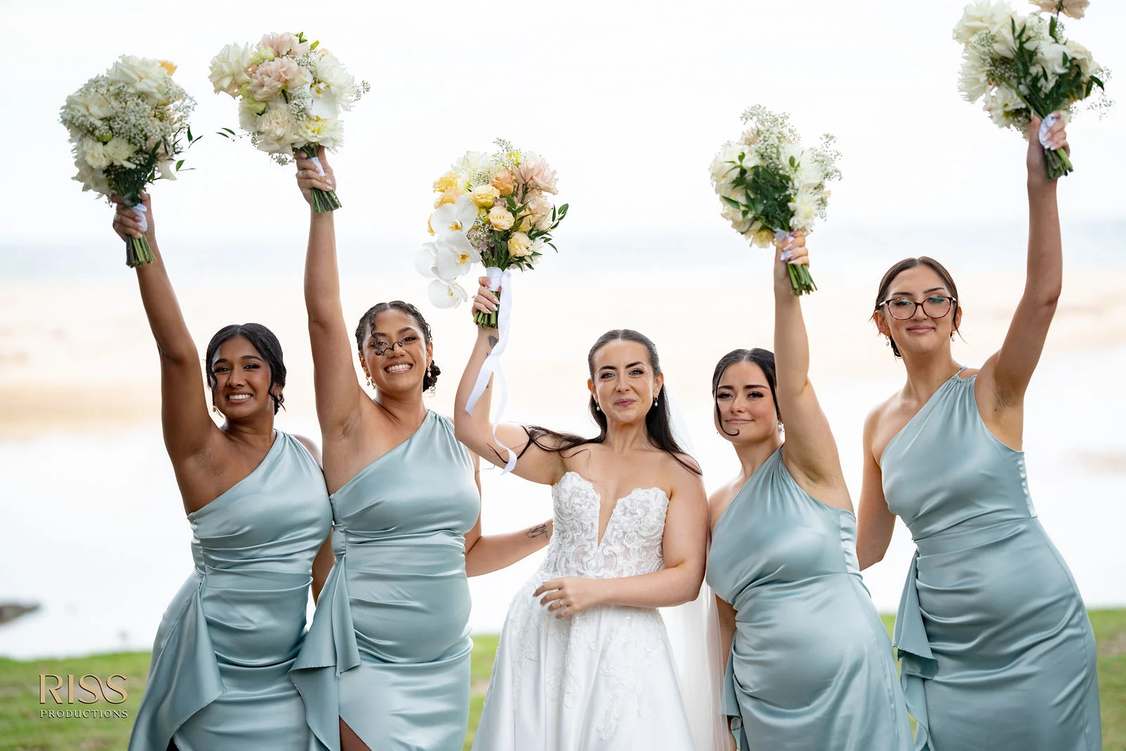 Bride and bridesmaids raising their bouquets in Wollongong