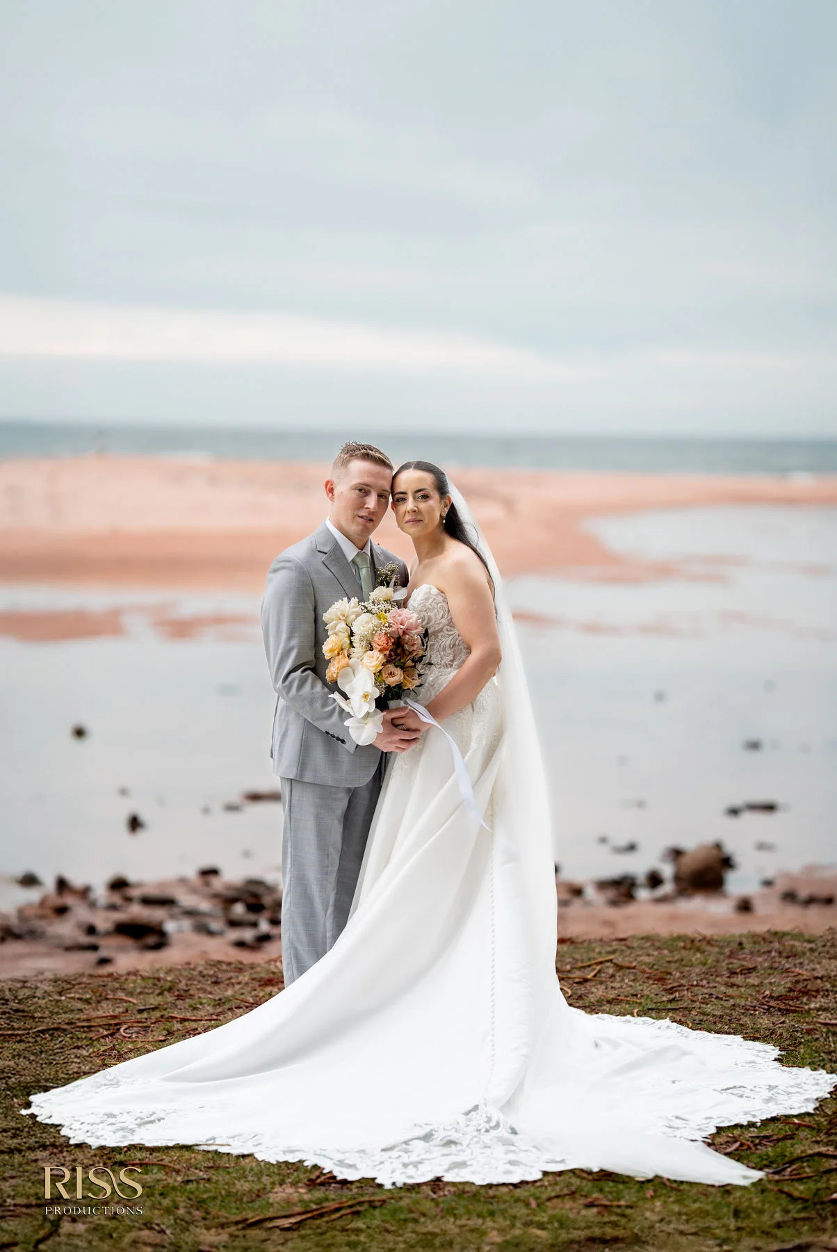 Meghan and Lachlan standing by the water with her long veil in Wollongong